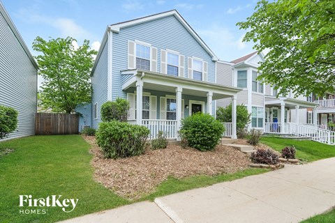 a blue house with a lawn and a sidewalk in front of it
