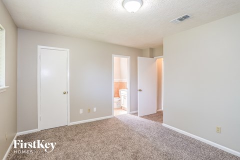 a spacious living room with carpet and a door to the bathroom