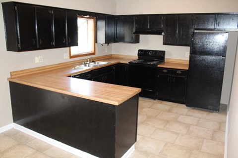 A kitchen with black cabinets and a wooden island.