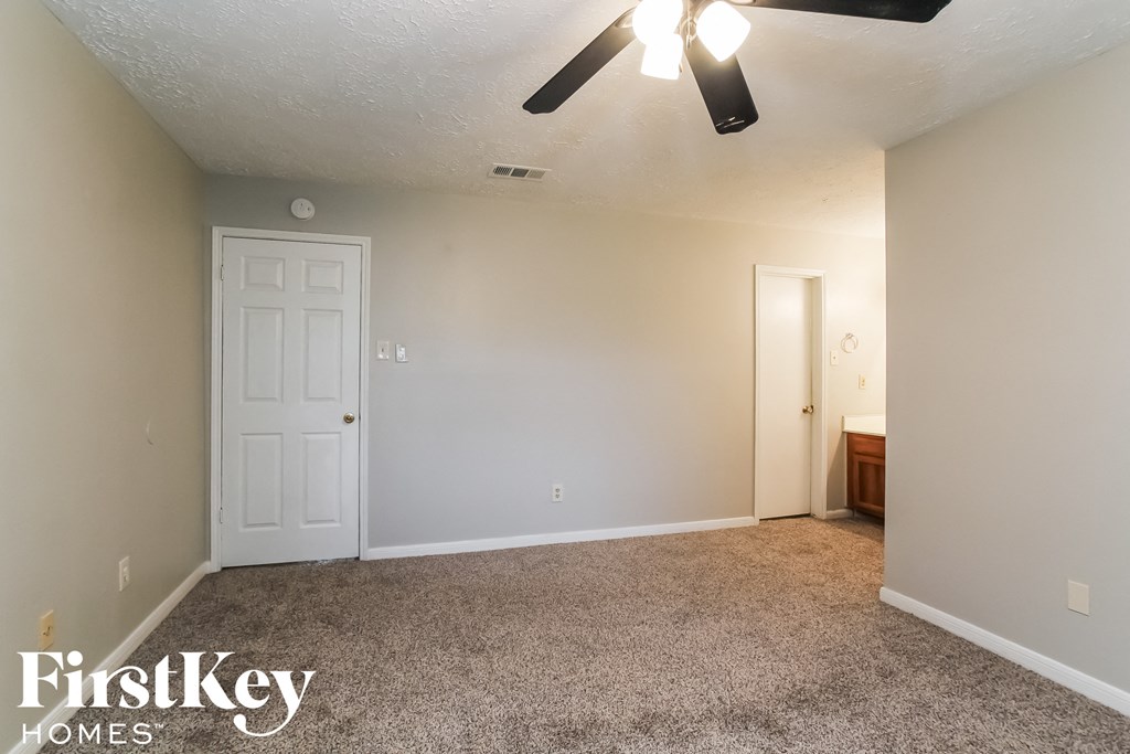 the living room of an empty house with a white door and a ceiling fan