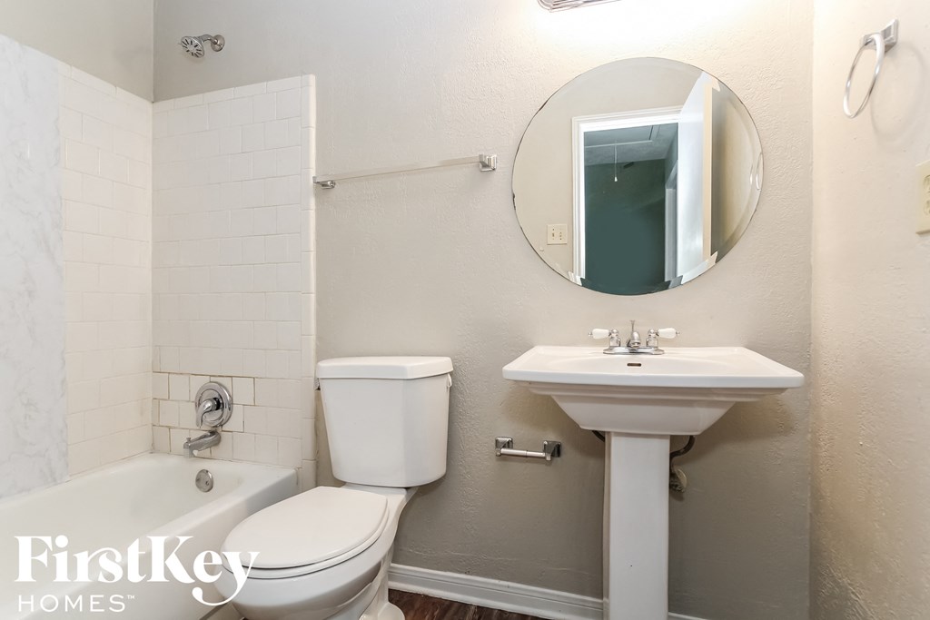 a white bathroom with a toilet sink and tub and a mirror