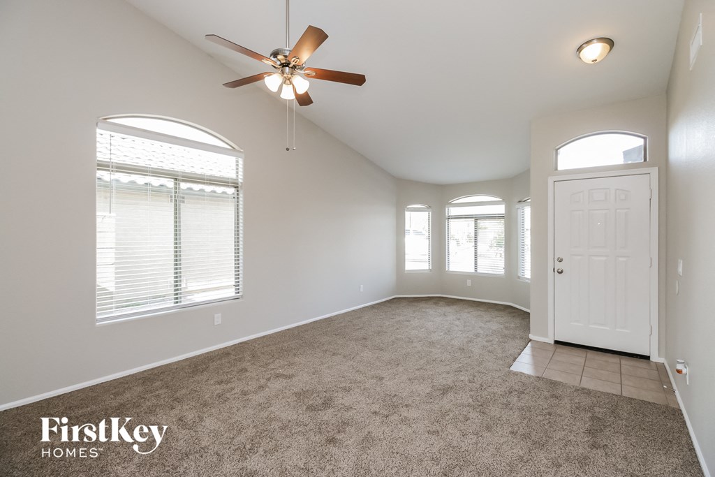an empty living room with a ceiling fan and a white door