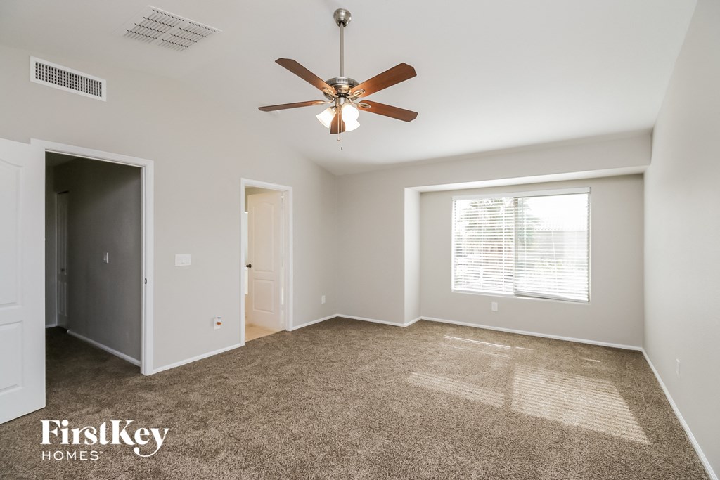 an empty living room with a ceiling fan and a window