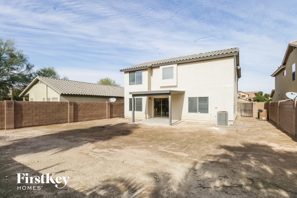 a large white house with a dirt driveway and a fence