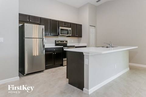 A kitchen with a stainless steel refrigerator, microwave, and oven.