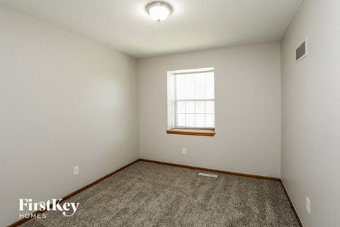 a bedroom with white walls and a window and a carpet