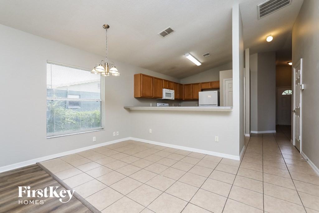 an empty living room with a kitchen and a large window