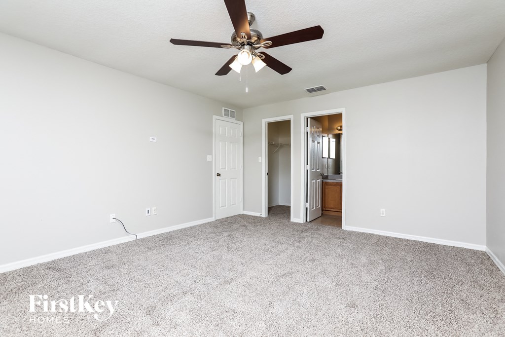 a spacious living room with carpet and a ceiling fan