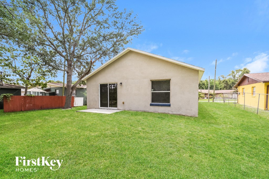 a small white house with a grass yard and a fence
