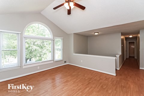 the living room and dining room with wood flooring and a ceiling fan