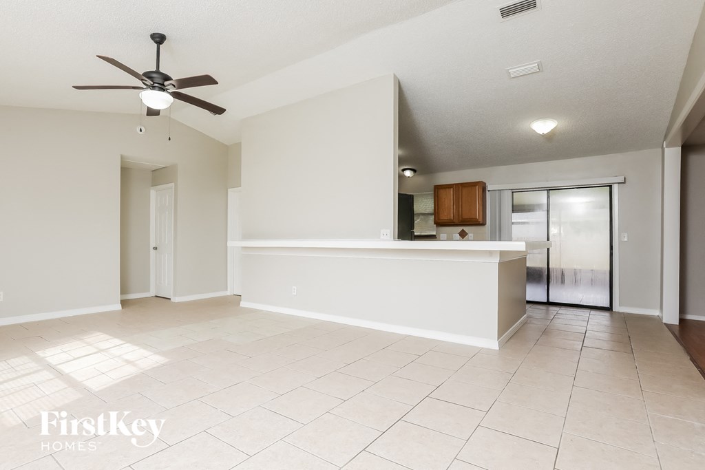 A spacious room with a ceiling fan and tiled flooring.