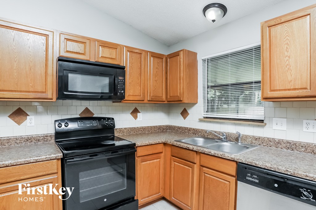 A kitchen with wooden cabinets and a black stove top oven.