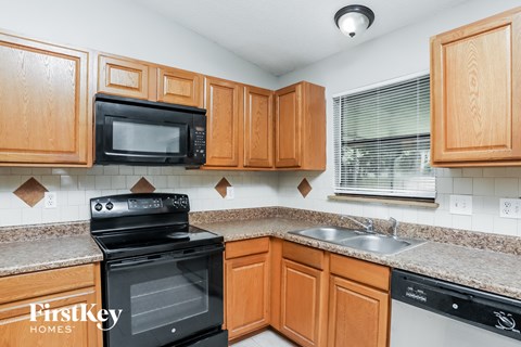 A kitchen with wooden cabinets and a black stove top oven.