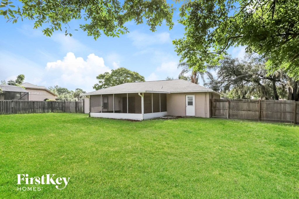 A house with a fence and trees in the background.