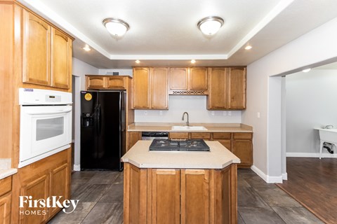 A kitchen with wooden cabinets and a black fridge.