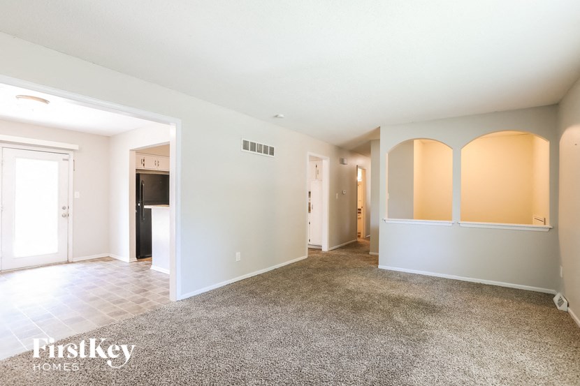 an empty living room with white walls and carpet