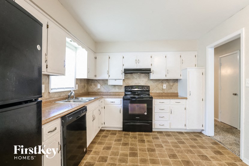 a kitchen with white cabinets and black appliances