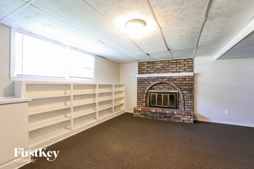a living room with a brick fireplace and a book shelf