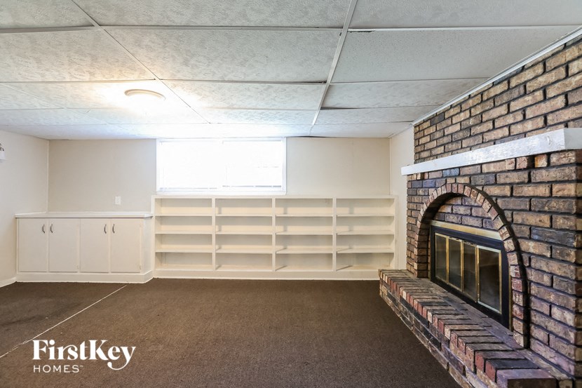 a living room with a brick fireplace and shelves