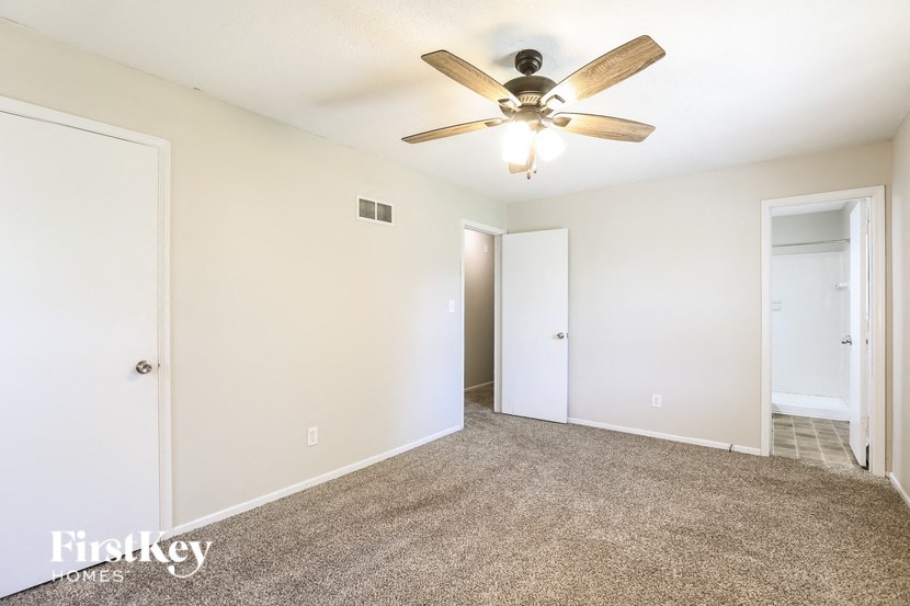 a empty living room with a ceiling fan and white walls