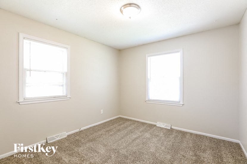 a bedroom with two windows and a carpeted floor