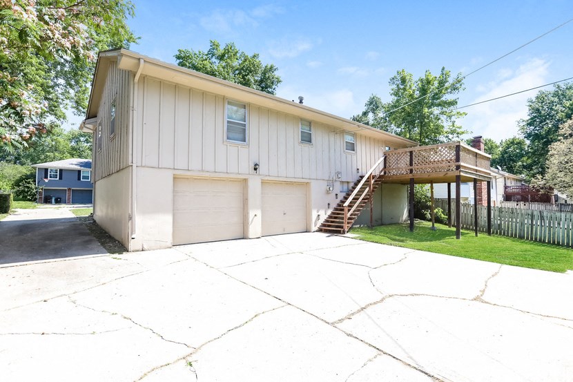 the front of a white house with two garage doors