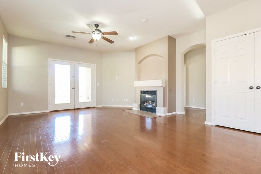 an empty living room with a fireplace and a ceiling fan