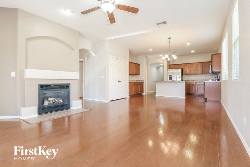 an empty living room with a fireplace and a kitchen