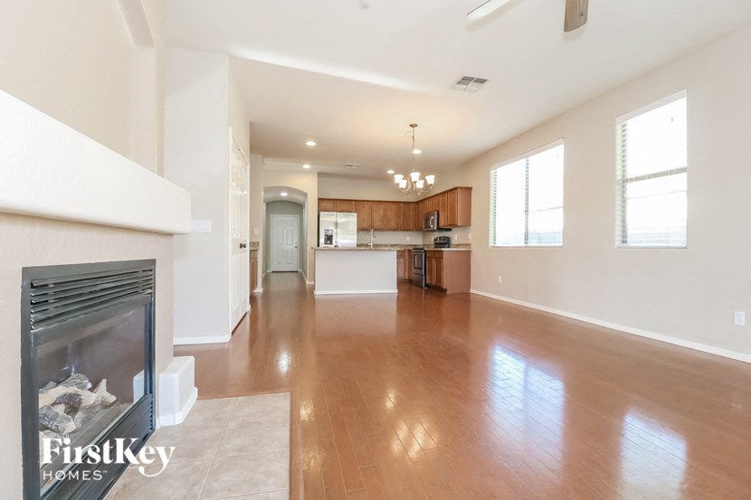 an empty living room with a fireplace and a kitchen