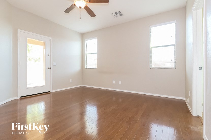 a empty living room with wood floors and a ceiling fan