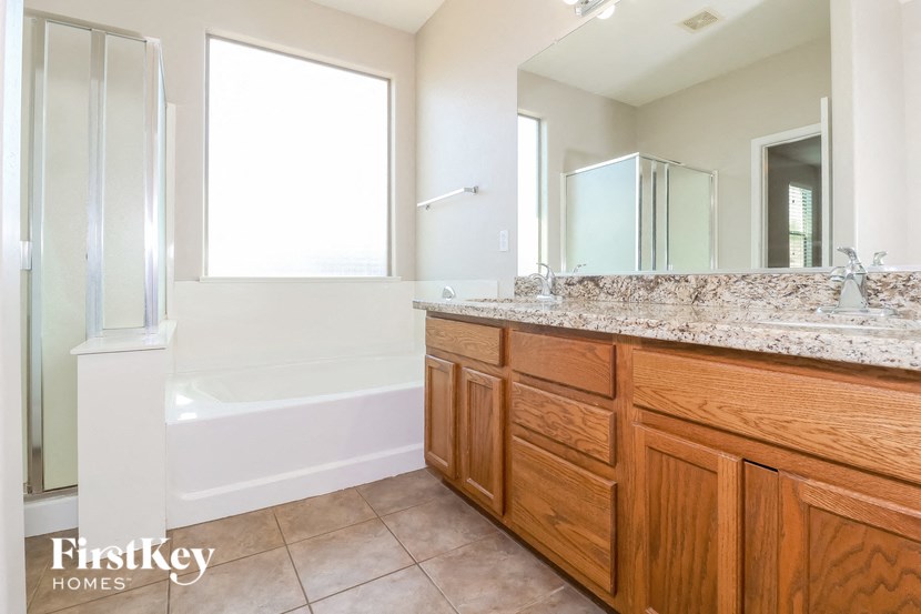 a bathroom with wooden cabinets and a tub and a sink