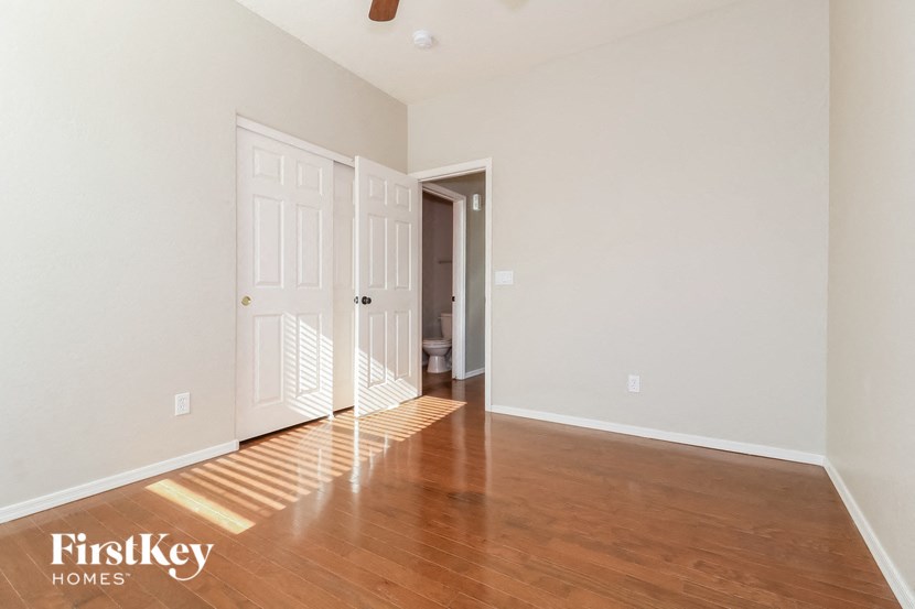 a living room with wood flooring and white walls and a door to a hallway