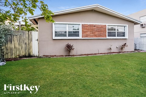 A house with a brown brick wall and a white fence.