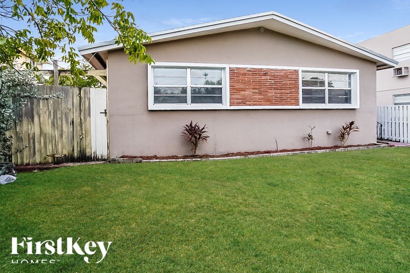 A house with a brown brick wall and a white fence.