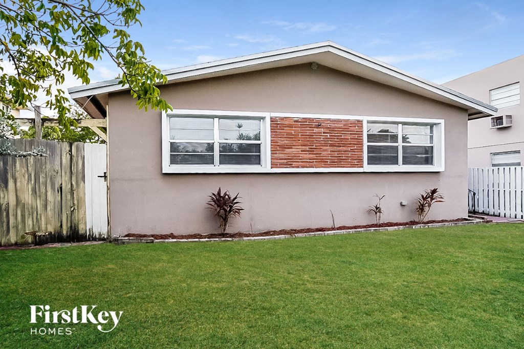 A house with a brown fence and a green lawn.