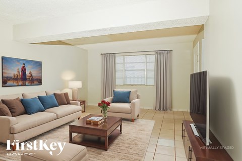 A living room with a couch, a coffee table, and a painting on the wall.