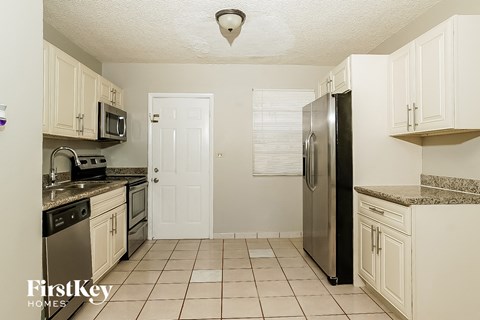 A kitchen with a refrigerator, microwave, and oven.