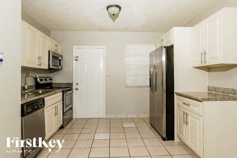 A kitchen with white cabinets and a black refrigerator.