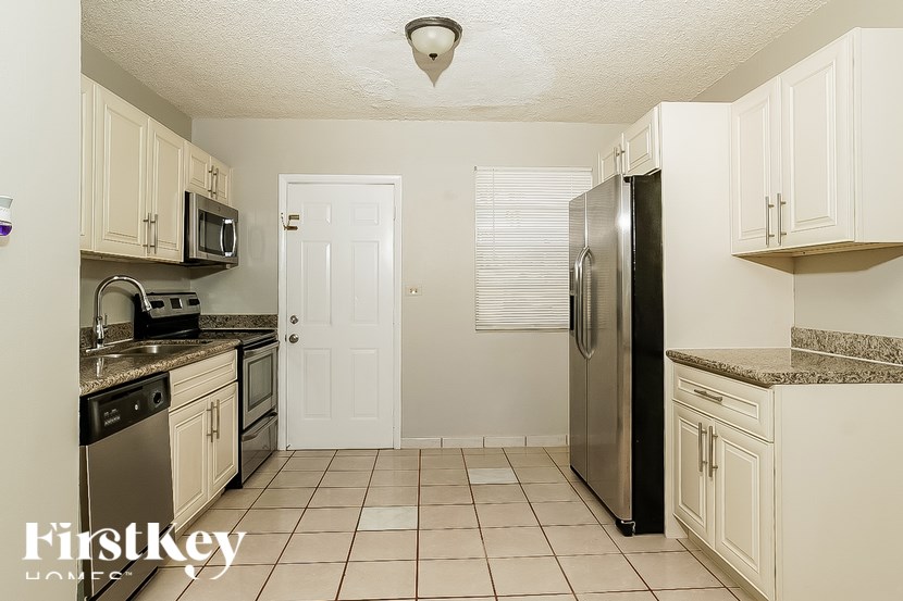 A kitchen with white cabinets and a black refrigerator.