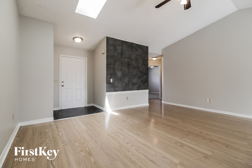 A spacious room with wooden flooring and a skylight.
