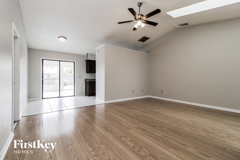 A spacious room with wooden flooring and a ceiling fan.