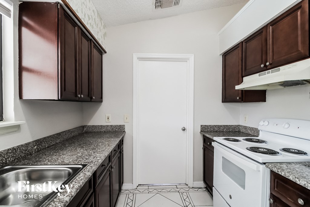 A kitchen with brown cabinets and a white stove top oven.