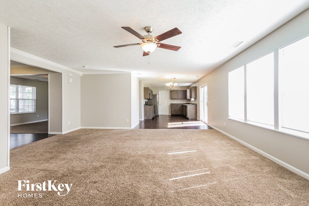 an empty living room with a ceiling fan and a carpet