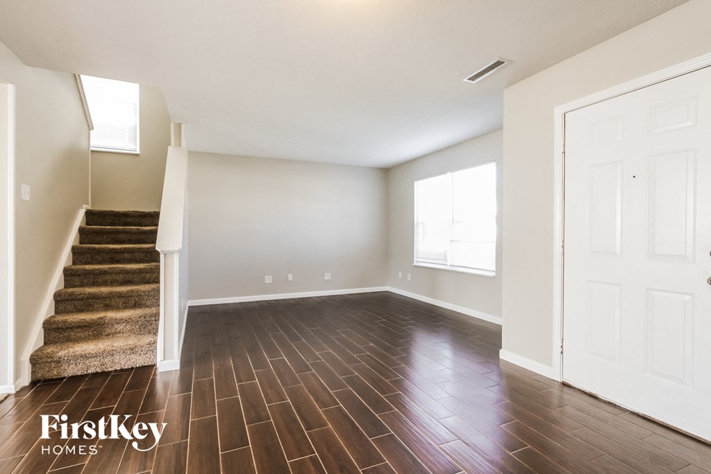 an empty living room with wood floors and a staircase