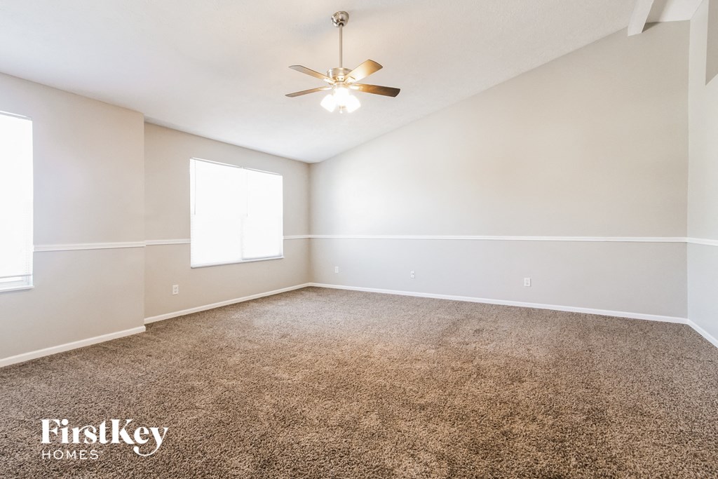 the spacious living room with carpeting and a ceiling fan