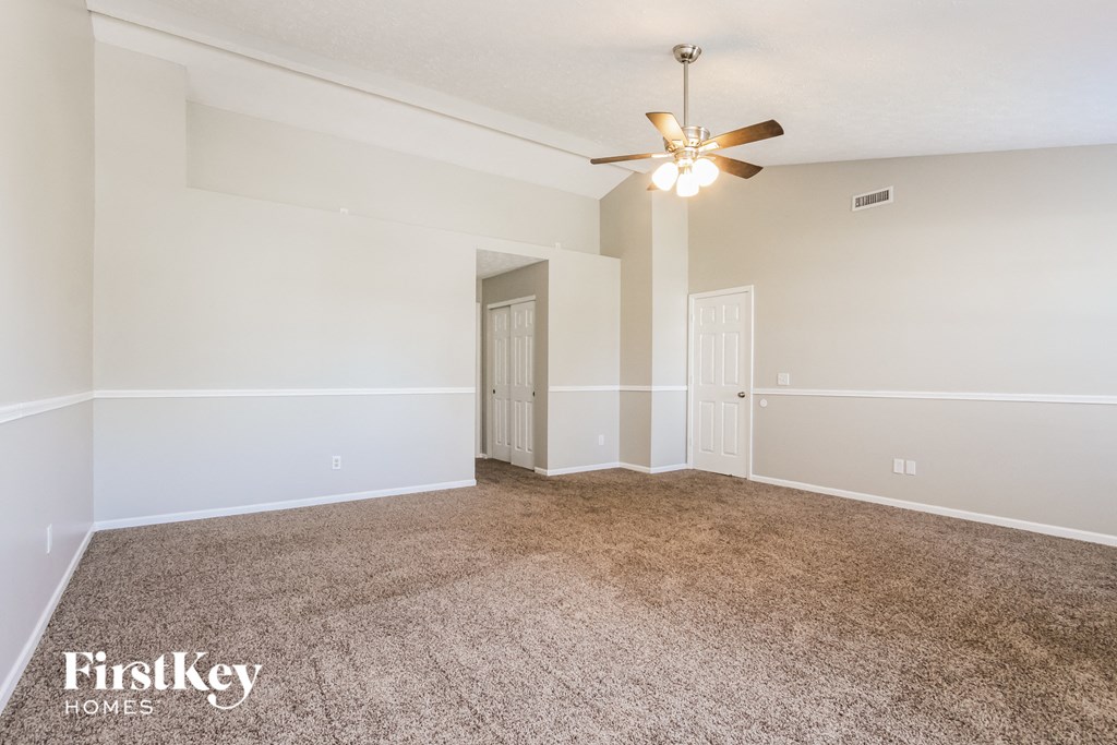 a spacious living room with carpet and a ceiling fan