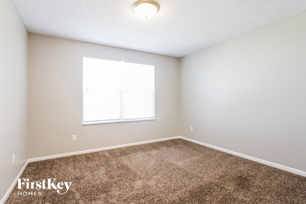 the spacious living room with carpeting and a window
