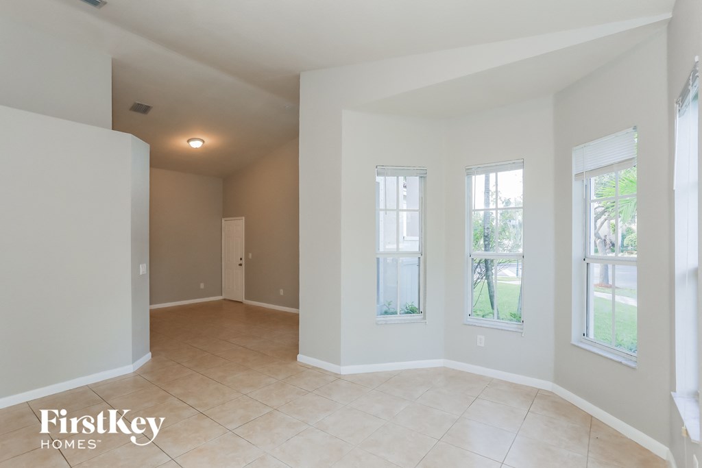 an empty living room with three windows and a tiled floor