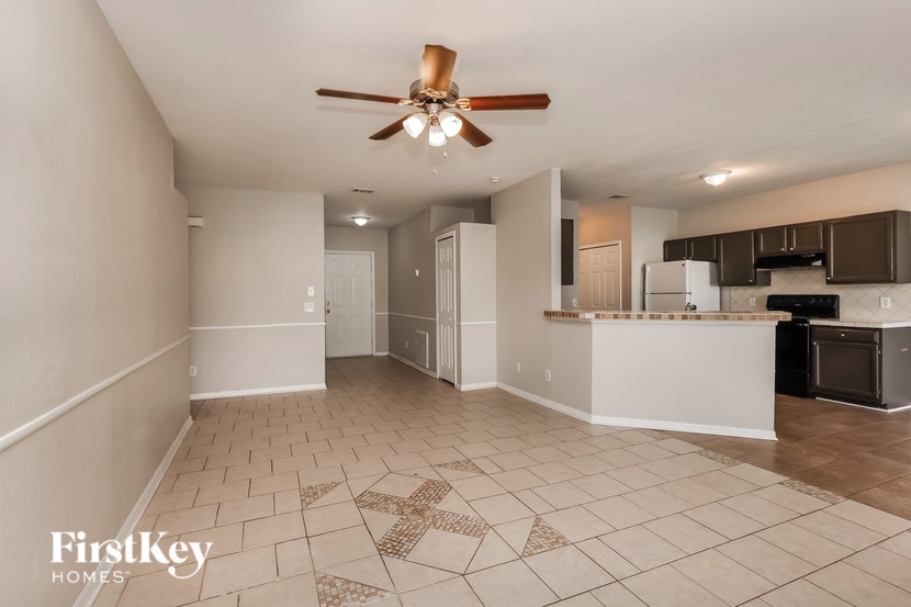 A spacious kitchen and living room with a tiled floor and a ceiling fan.