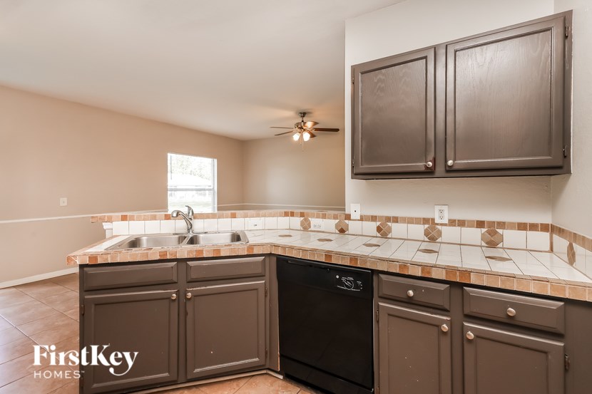 A kitchen with brown cabinets and a black dishwasher.